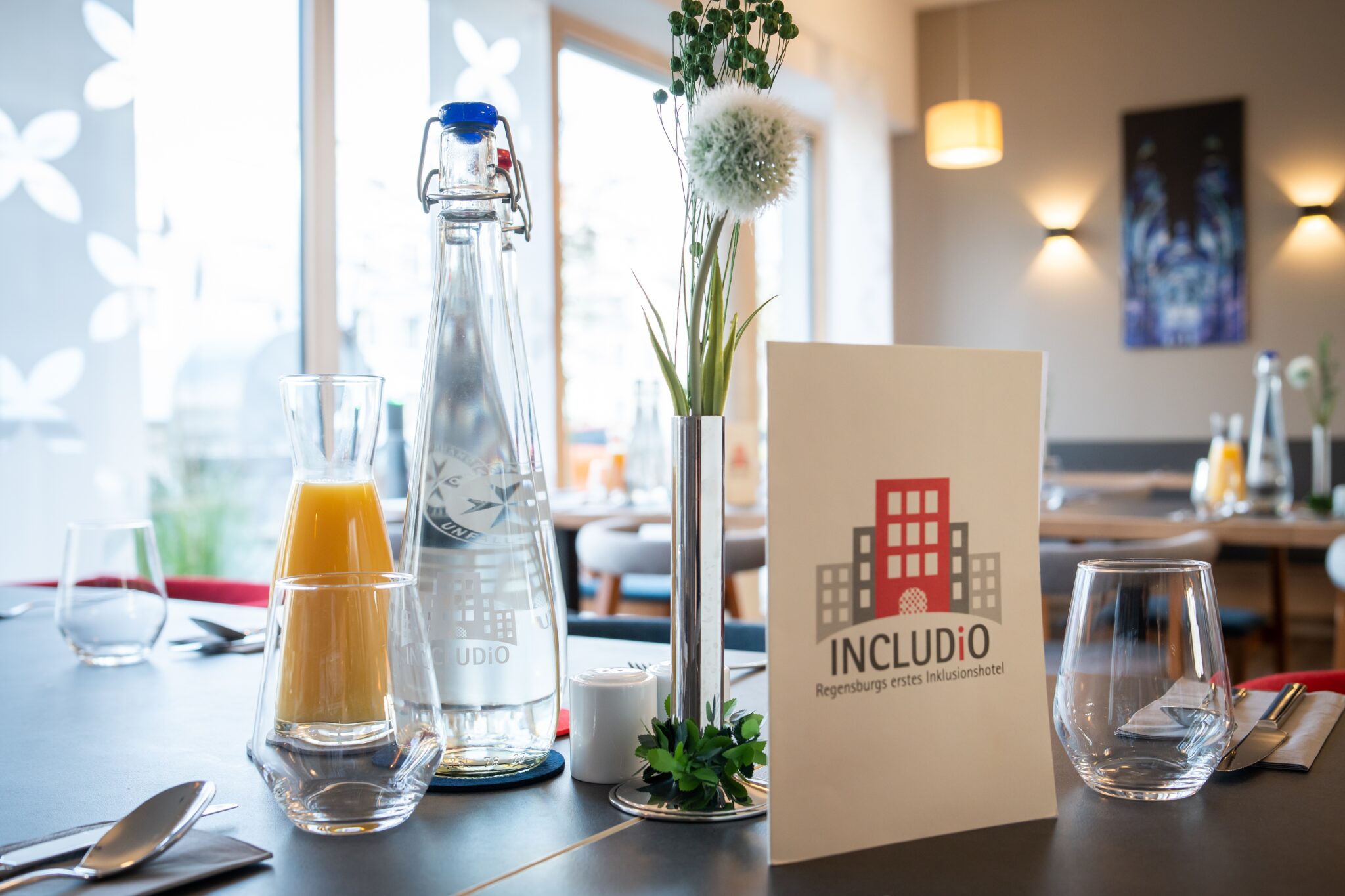 Tisch mit Meneralwasser, Saft und Speisekarte im Hotel INCLUDiO Regensburg