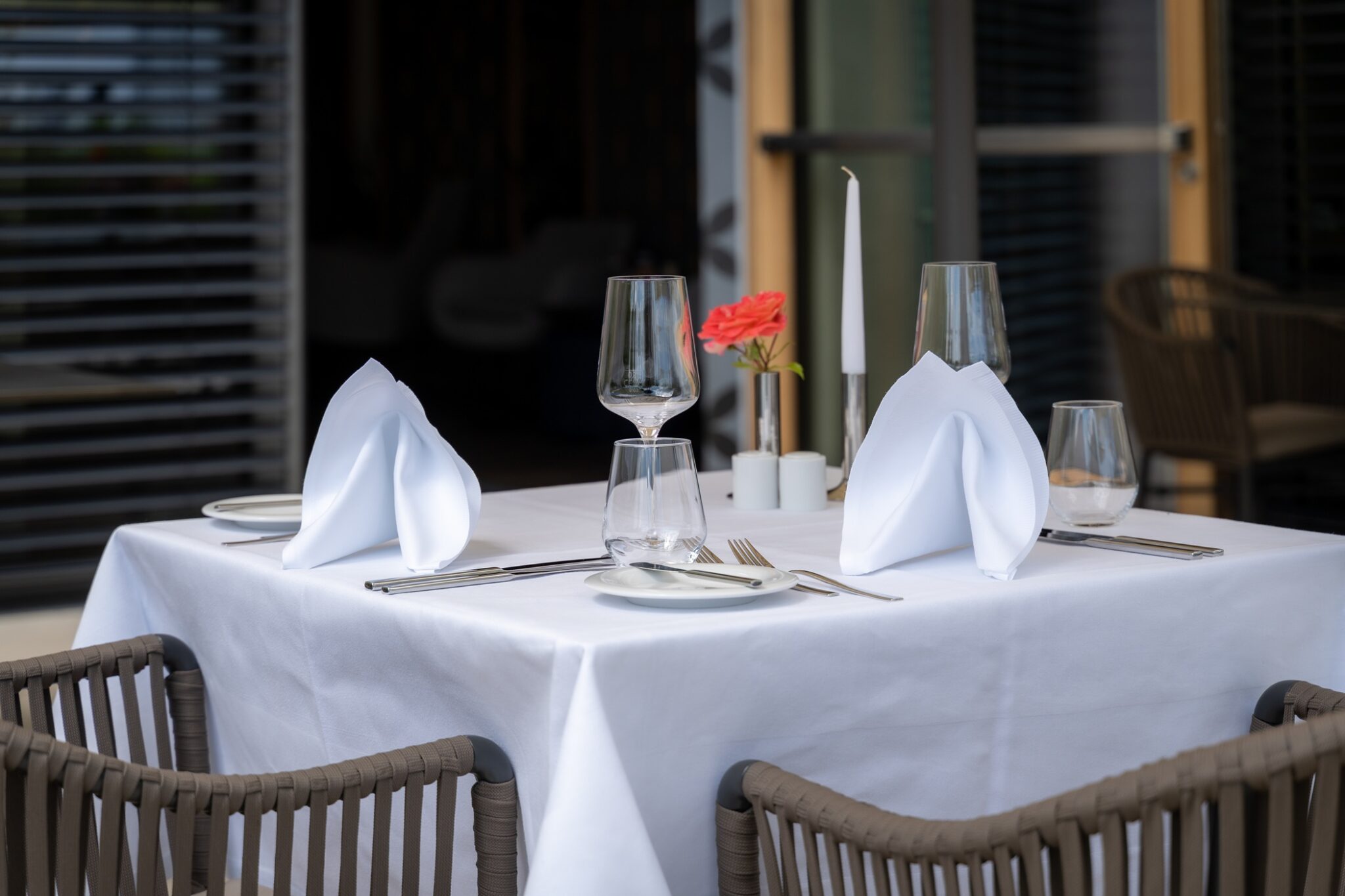 Eleganter Tisch mit weißer Tischdecke, Gläsern und Besteck in unserem Restaurant.